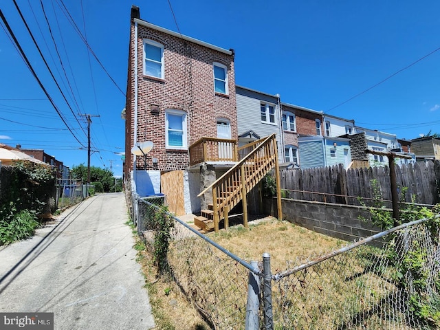 rear view of house featuring a fenced front yard, brick siding, and stairway