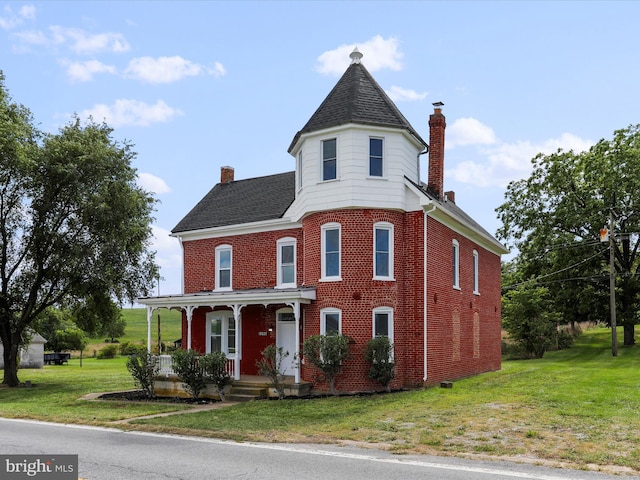 victorian house featuring brick siding, a chimney, a shingled roof, and a front lawn