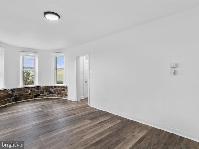 empty room with dark wood-type flooring and baseboards