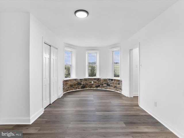 empty room with dark wood-type flooring and baseboards