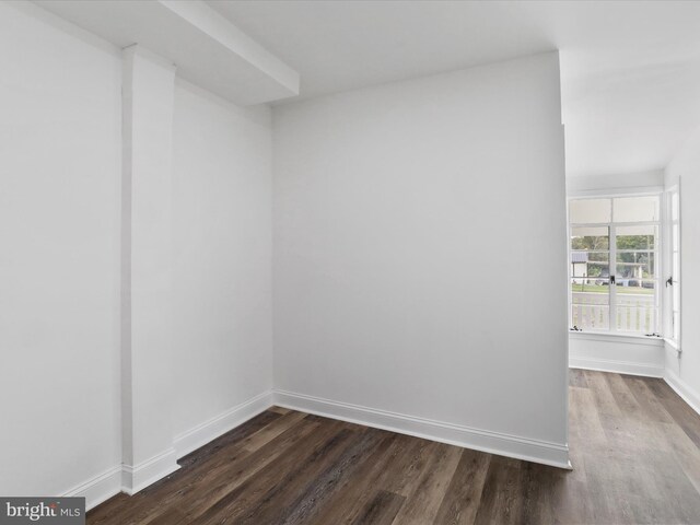 spare room with dark wood-style floors and baseboards