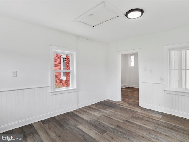 unfurnished room featuring dark wood-style floors and wainscoting