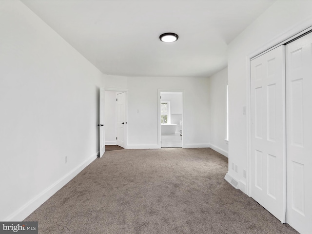 unfurnished bedroom with a closet, dark carpet, visible vents, and baseboards