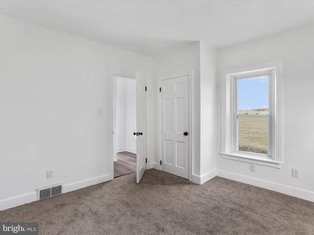 unfurnished bedroom with carpet floors, visible vents, and baseboards