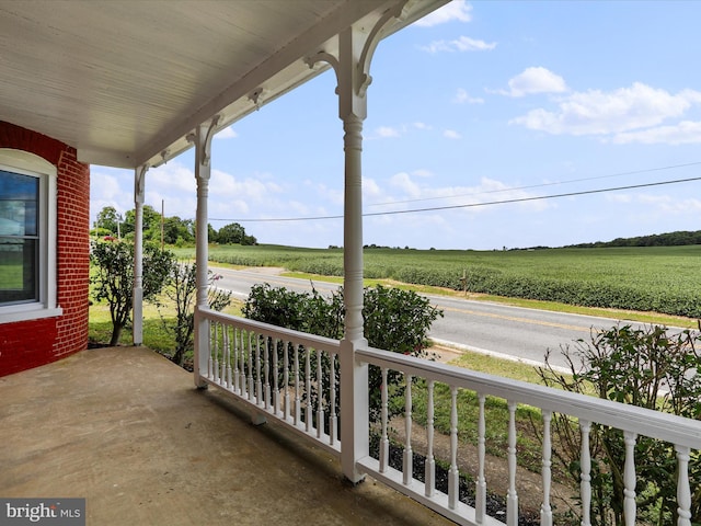 balcony featuring covered porch and a rural view