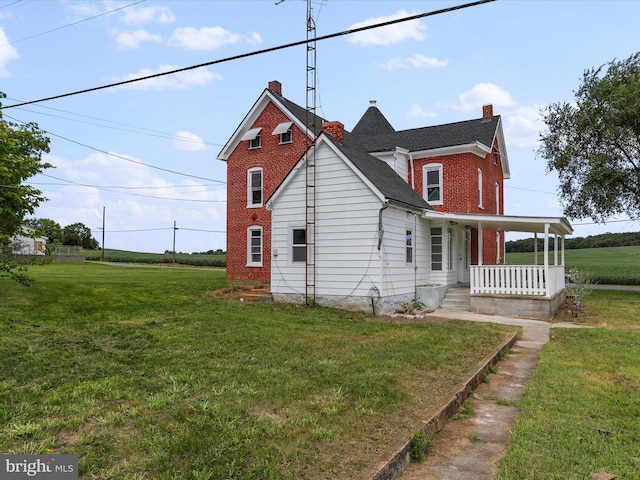 exterior space featuring a yard, a chimney, a porch, and brick siding