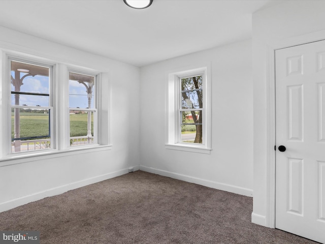 spare room featuring baseboards and dark carpet