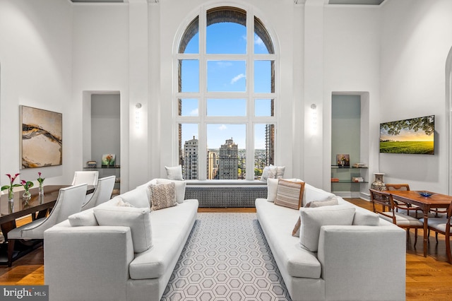 living room featuring a towering ceiling, hardwood / wood-style flooring, and a wealth of natural light