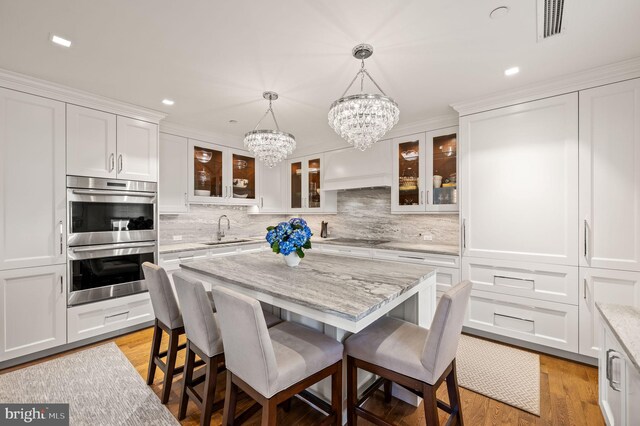 kitchen with sink, light stone countertops, a chandelier, and double oven