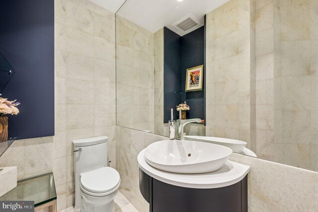 bathroom with vanity, tile walls, and toilet