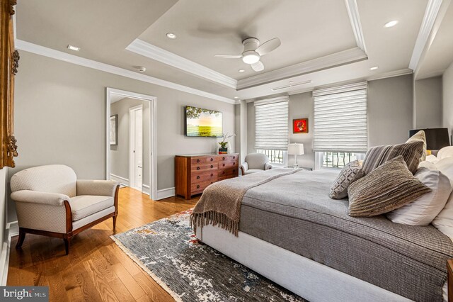 bedroom with ornamental molding, a raised ceiling, wood-type flooring, and ceiling fan