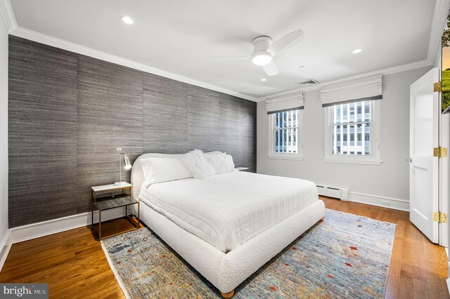 bedroom with ceiling fan, a baseboard radiator, wood-type flooring, and ornamental molding