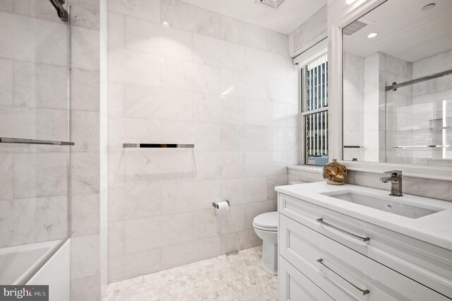 bathroom with vanity, toilet, tile walls, and a tile shower