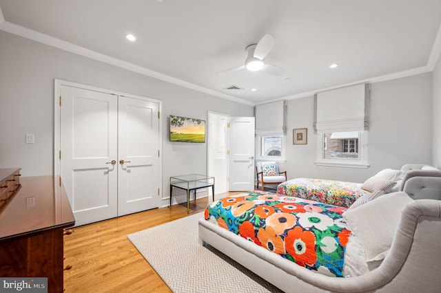 bedroom with light hardwood / wood-style flooring, ceiling fan, ornamental molding, and a closet