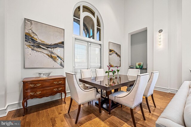 dining room with wood-type flooring and a towering ceiling