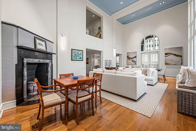 dining room with a high ceiling, wood-type flooring, and a high end fireplace