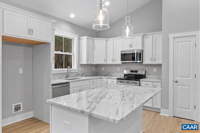 kitchen featuring white cabinets, pendant lighting, appliances with stainless steel finishes, and a kitchen island