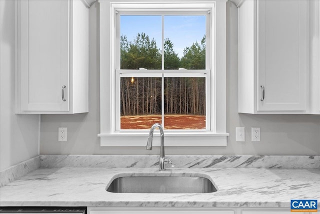 kitchen with light stone countertops, sink, white cabinets, and a healthy amount of sunlight