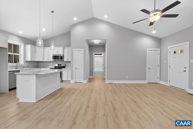 kitchen with light stone countertops, appliances with stainless steel finishes, white cabinets, a kitchen island, and pendant lighting