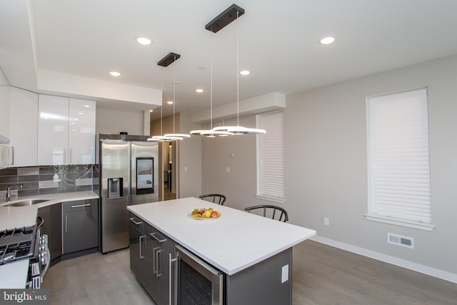 kitchen featuring pendant lighting, white cabinetry, beverage cooler, a kitchen island, and light hardwood / wood-style floors