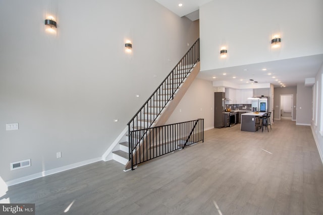 stairway featuring a towering ceiling and wood-type flooring