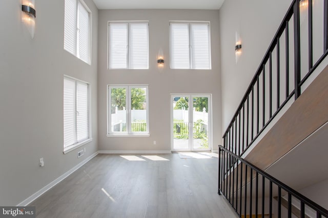 entryway featuring a towering ceiling and light hardwood / wood-style floors