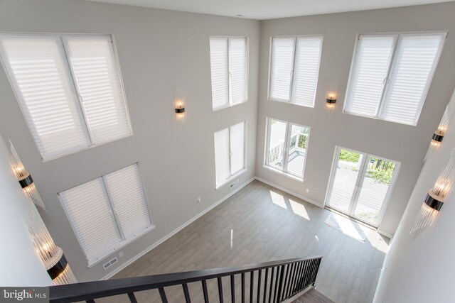 staircase with hardwood / wood-style floors and a high ceiling