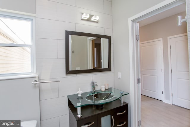 bathroom with vanity, wood-type flooring, tasteful backsplash, tile walls, and toilet