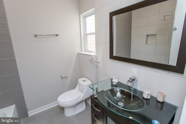 bathroom featuring vanity, toilet, a bath, and tile walls