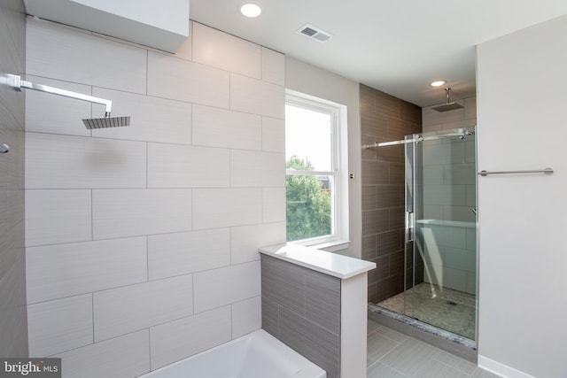 bathroom with a tile shower and tile patterned flooring