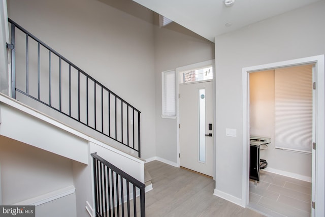 foyer featuring light wood-type flooring and a towering ceiling