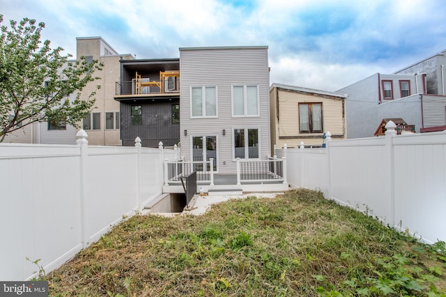 rear view of property featuring a balcony and a yard