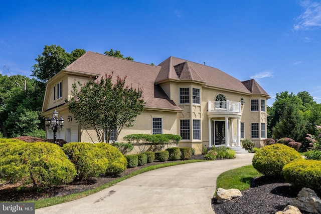 french provincial home with a garage and a balcony