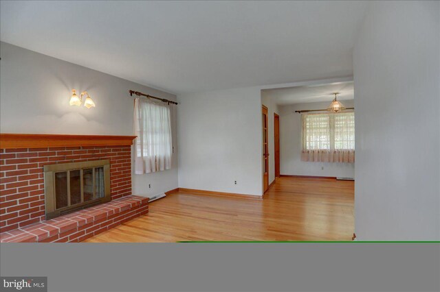 unfurnished living room with hardwood / wood-style floors and a brick fireplace