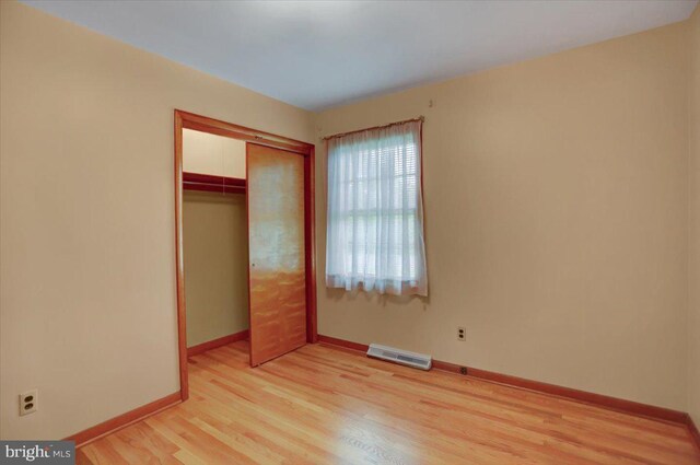 unfurnished bedroom with light hardwood / wood-style flooring and a closet