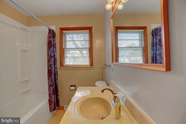 full bathroom with toilet, shower / bathtub combination with curtain, vanity, and a healthy amount of sunlight