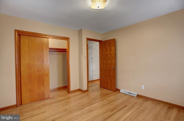 unfurnished bedroom with a closet and light wood-type flooring