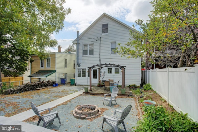 rear view of property featuring a fire pit, a fenced backyard, and a pergola