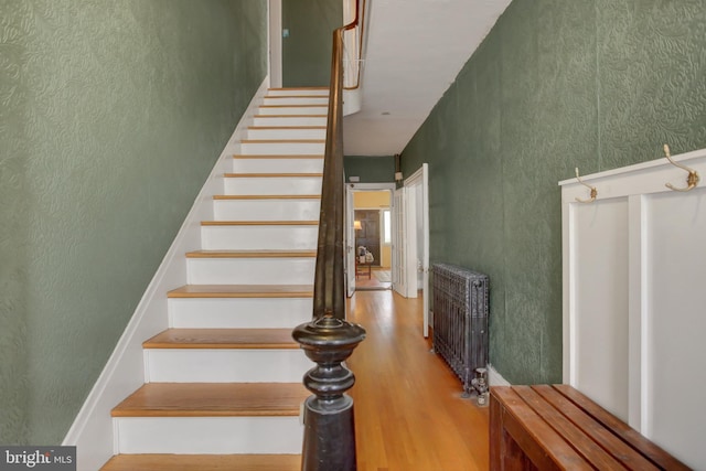 stairs featuring radiator and wood finished floors