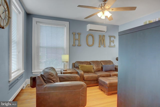 living area with light wood-type flooring, ceiling fan, baseboards, and a wall mounted air conditioner