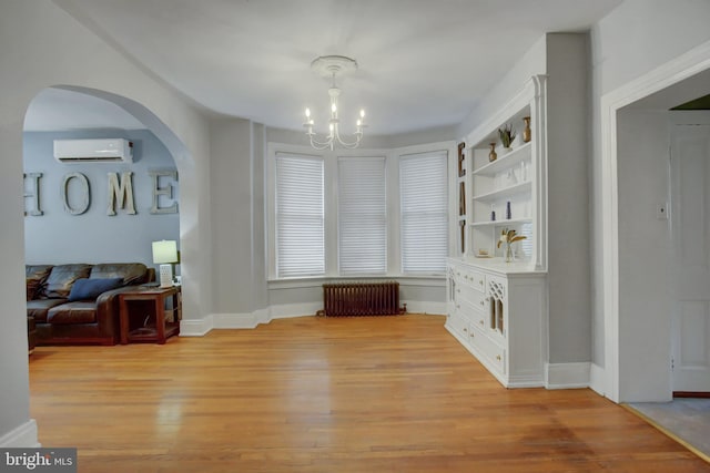 dining room with arched walkways, radiator, a wall unit AC, an inviting chandelier, and light wood-style floors