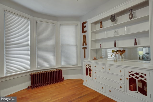 interior space with radiator heating unit, light wood-style flooring, and baseboards