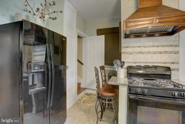 kitchen with backsplash, white cabinetry, black appliances, premium range hood, and a kitchen breakfast bar