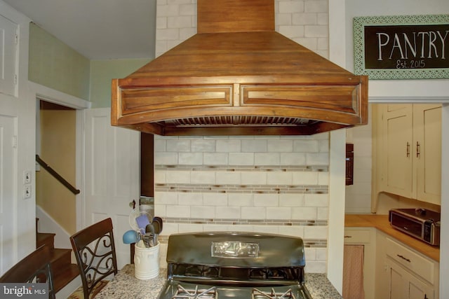 kitchen with premium range hood, light stone counters, and tasteful backsplash