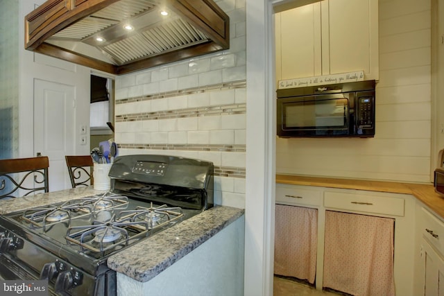 kitchen featuring black appliances, tasteful backsplash, light stone counters, and custom range hood