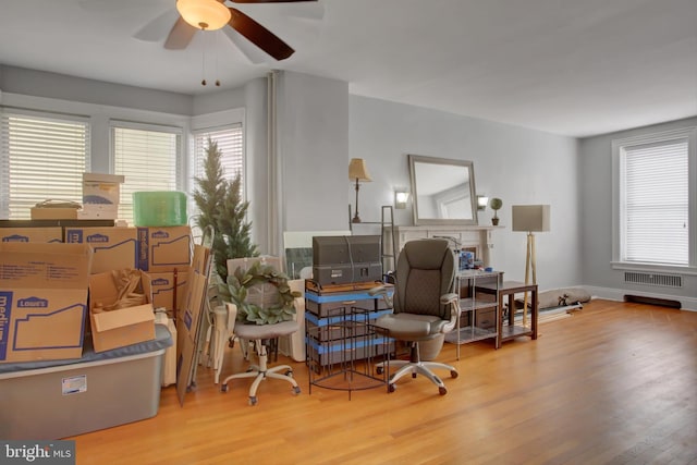 interior space featuring radiator, wood finished floors, a ceiling fan, and baseboards