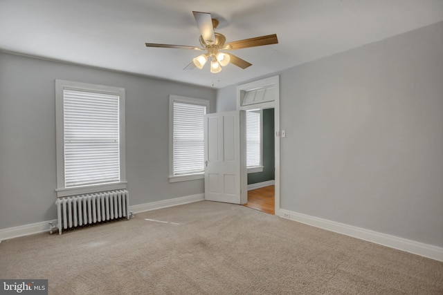 unfurnished bedroom with baseboards, light colored carpet, ceiling fan, and radiator heating unit