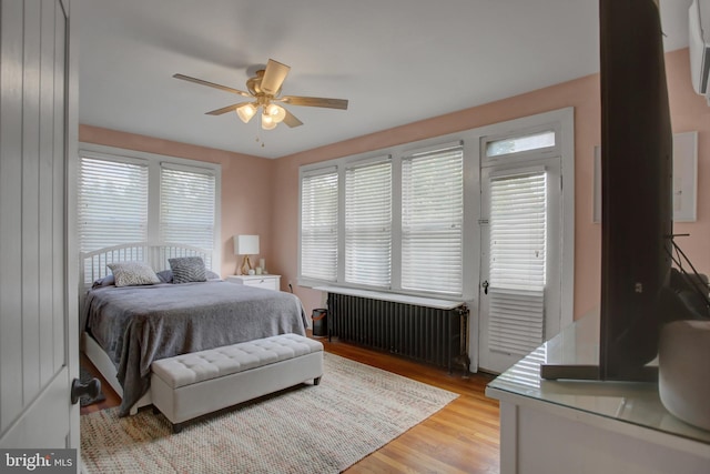 bedroom featuring light wood finished floors, a ceiling fan, and radiator