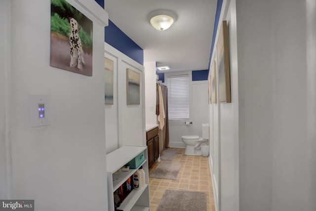 bathroom featuring toilet, baseboards, and vanity