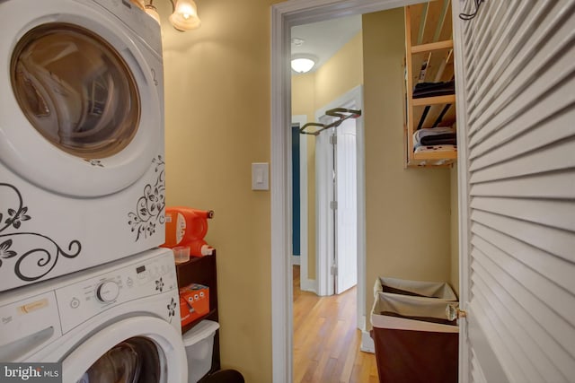 washroom featuring stacked washer and clothes dryer, light wood finished floors, and laundry area